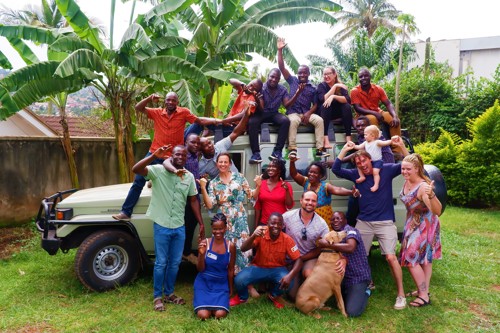 Gruppenbild von Roadtrip Uganda-Mitarbeitern vor einem grünen Landcruiser